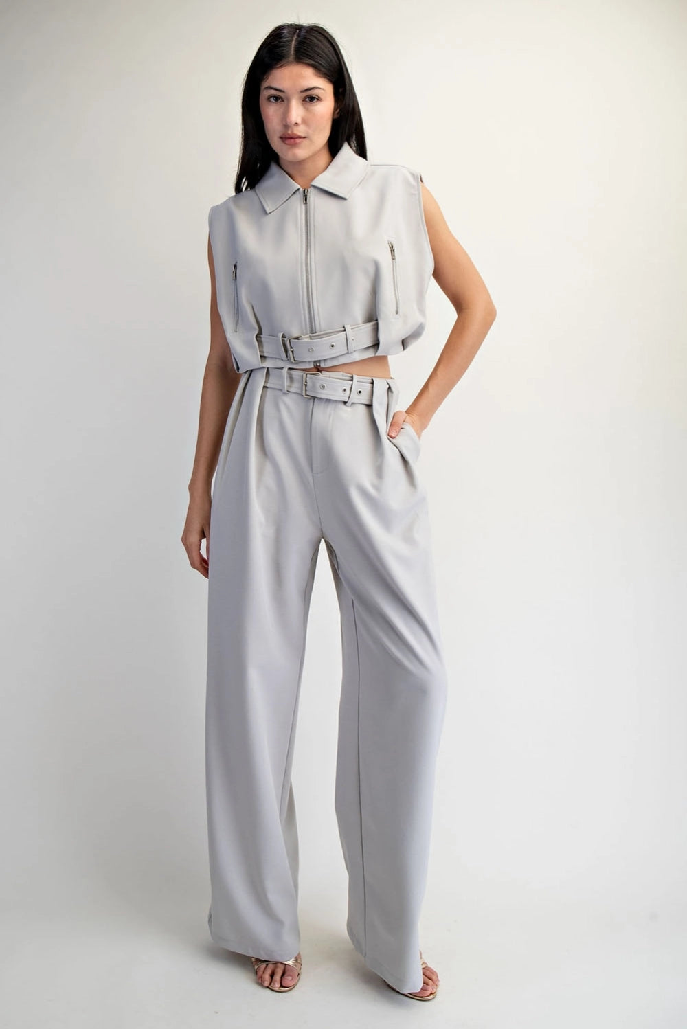 Woman wearing a light gray sleeveless top and wide-leg pants on a white background