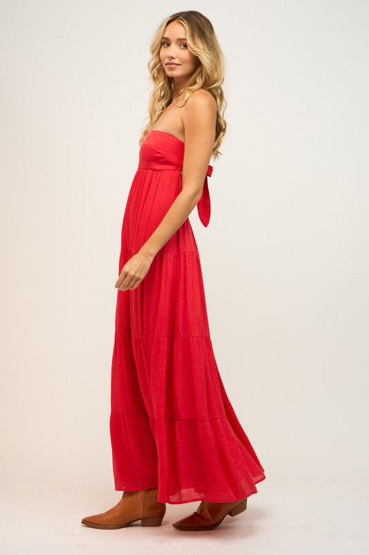 Woman wearing a red strapless dress with a bow detail on a white background