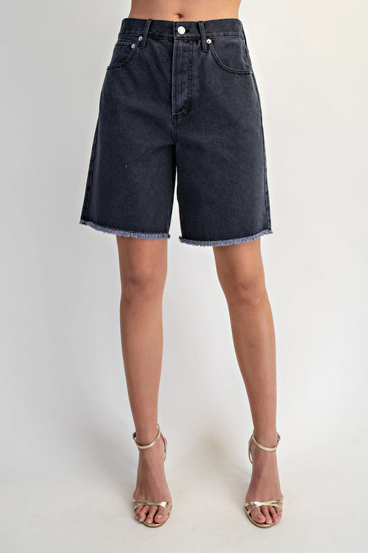 Black denim shorts worn by a person on a plain background